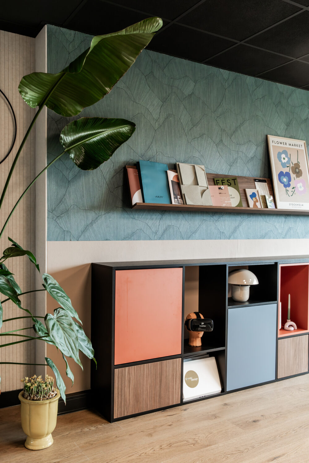 Kleurrijke kast tegen muur met blauw behang in de studio van Combi Design