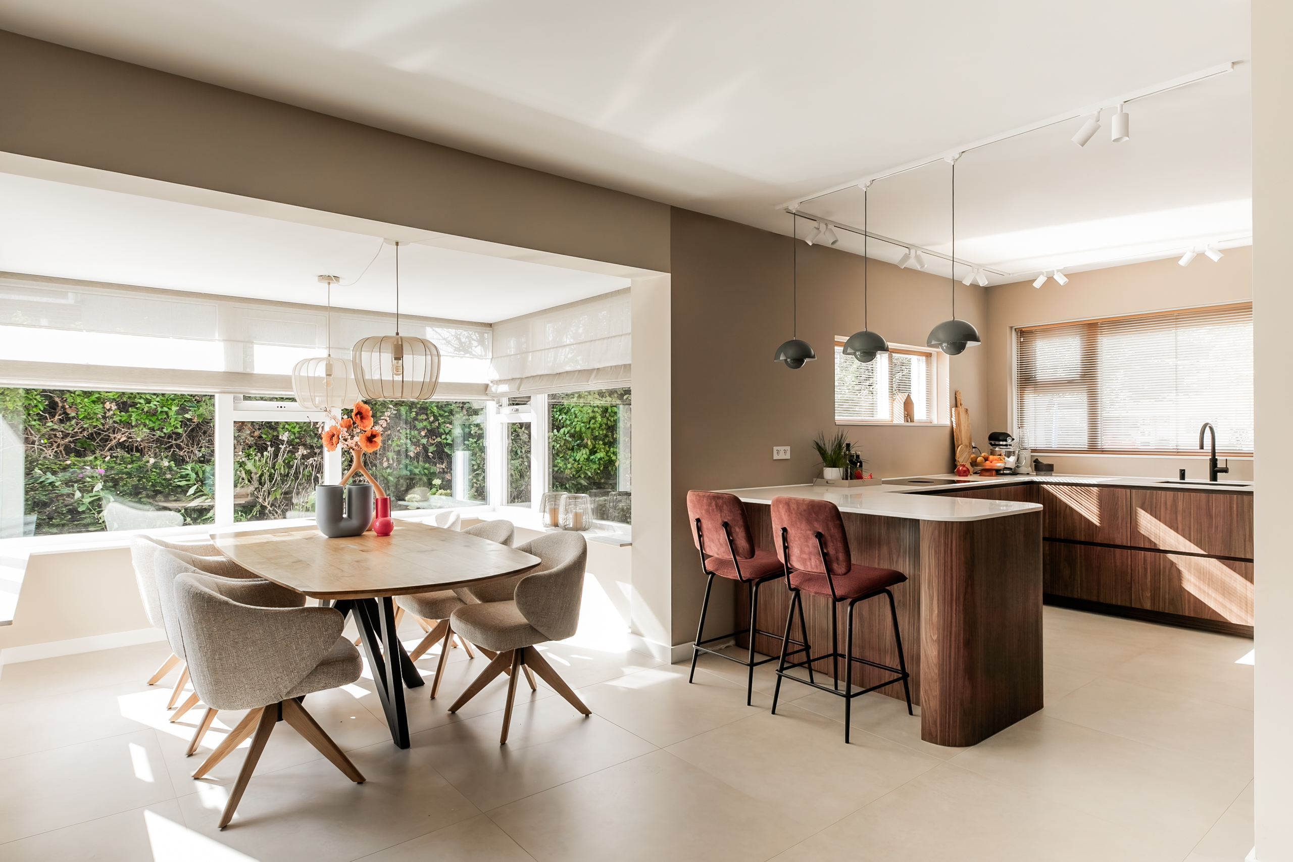 Beige interieur met kleurrijke accessoires, grote groene bank, piano in maatwerkkast